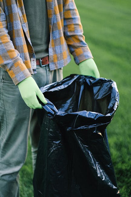 A person wearing light blue jeans and white sneakers is crouching on a paved outdoor surface, holding a small, partially broken white ceramic object with a smooth finish in their right hand. The ceram